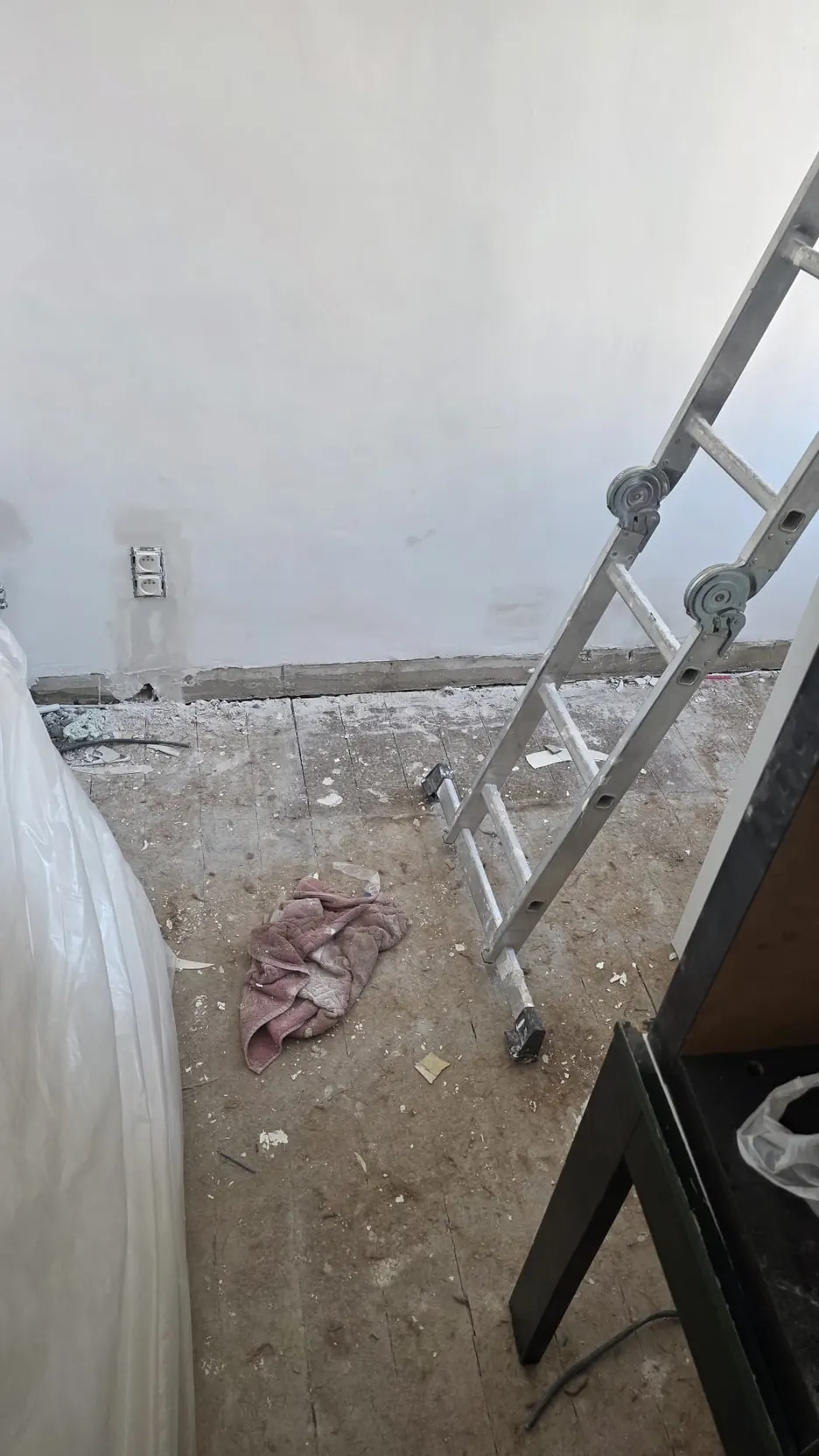 Pièce avec une échelle et un sol encore marqué par le chantier avant le nettoyage
